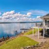 Panoramic view of a beautiful, large modern luxury summer holiday home, featuring sun decks, glass railings, and large windows, set beside a small lake in central British Columbia, Canada. Panoramic view of a beautiful, large modern luxury summer holiday home, featuring sun decks, glass railings, and large windows, set beside a small lake in central British Columbia, Canada.