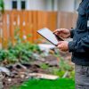 Gardener using tablet to plan landscape design in a residential backyard renovation Gardener using tablet to plan landscape design in a residential backyard renovation
